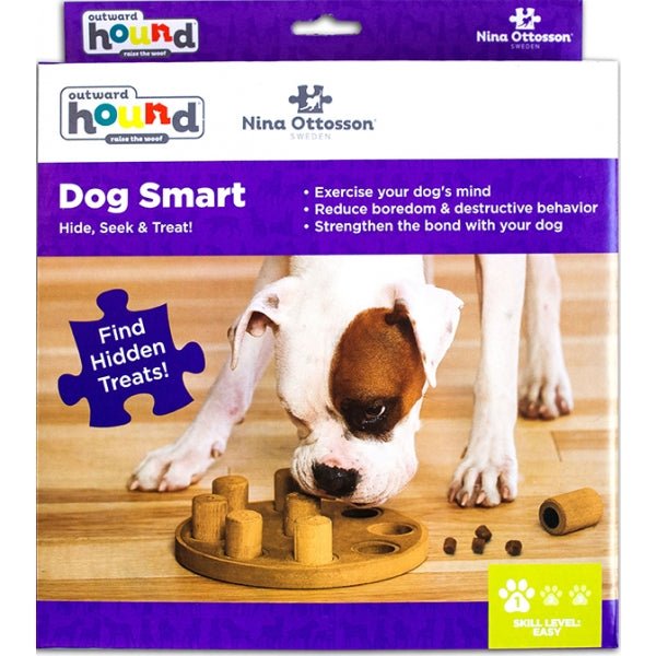 Dog toy packaging with a dog interacting with the toy on a wooden floor, featuring Outward Hound and Nina Ottosson branding.